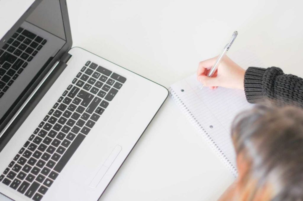 A woman using a computer and notepad to calculate rent on her investment property