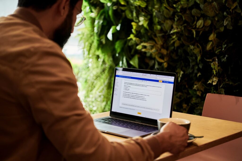 A man sitting in front of his computer signing an electronic property management contract