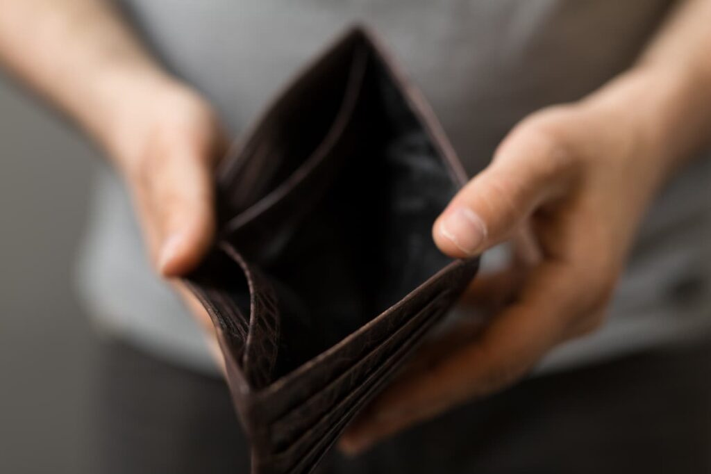 a person holds their empty wallet open to signal the effects of an economic recession