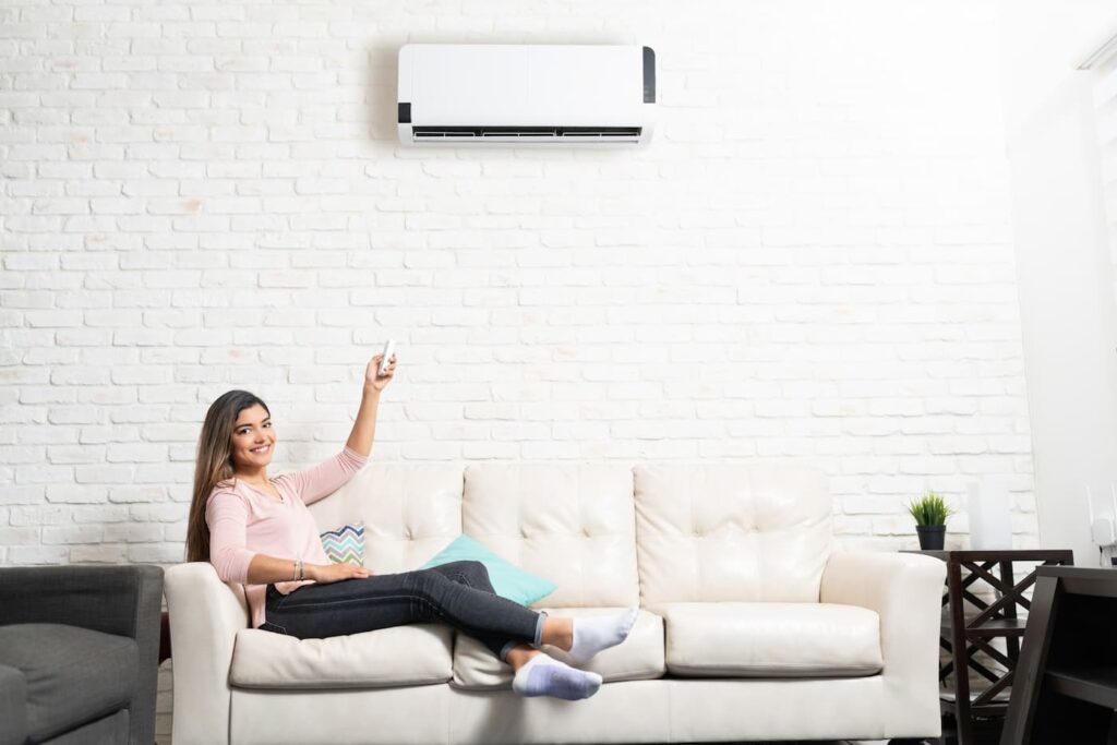 A smiling woman adjust the temperature on her AC unit to reduce energy usage