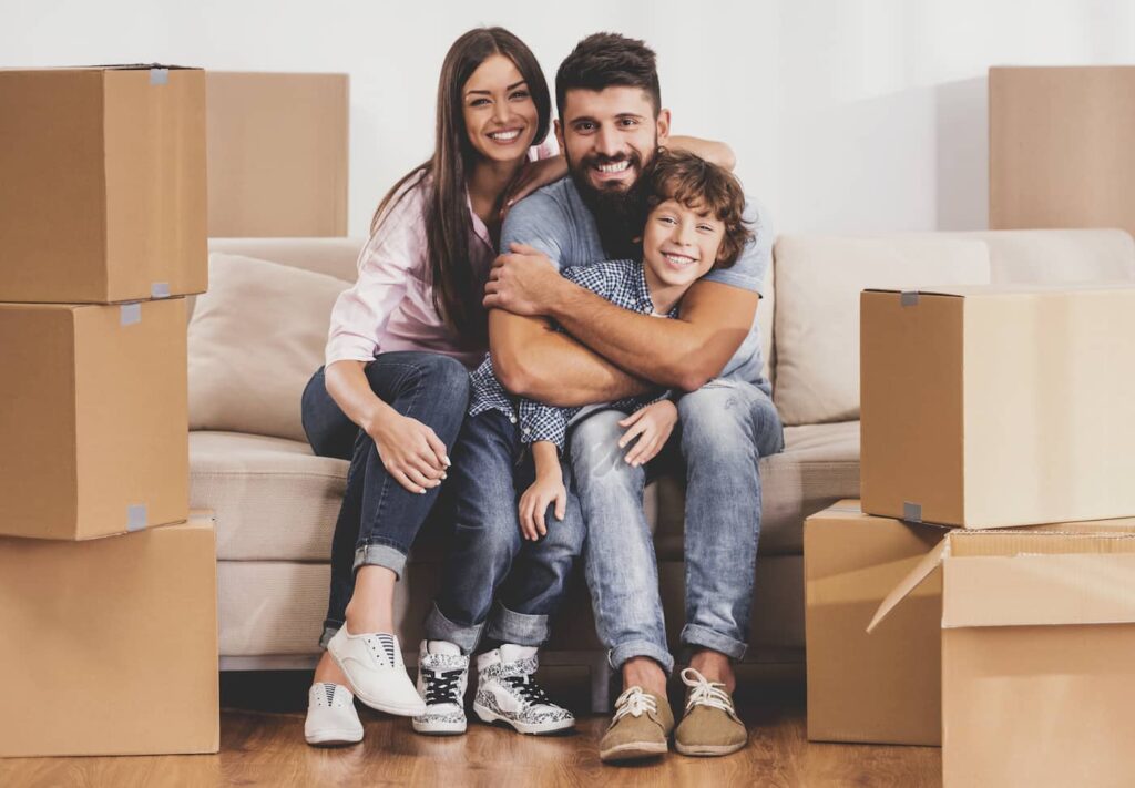 a family that received a housing voucher smiling together among moving boxes