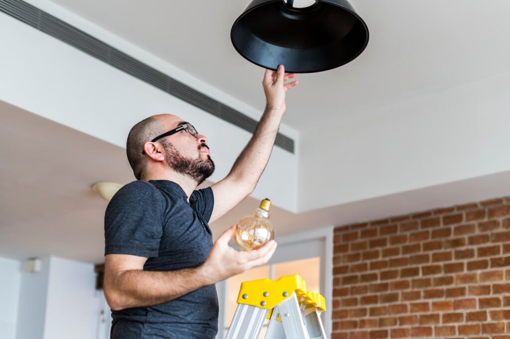 A man changing a lightbulb, one of the top home maintenance tasks in Portland.