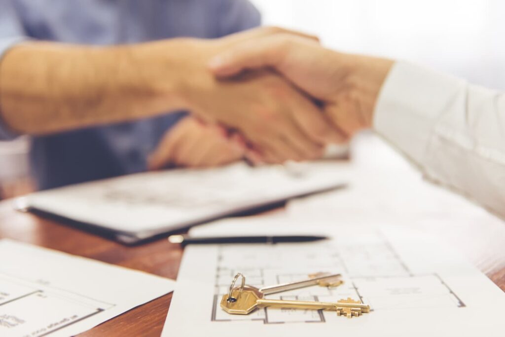 A homeowner shakes hands over paperwork as they start working with a property management company.