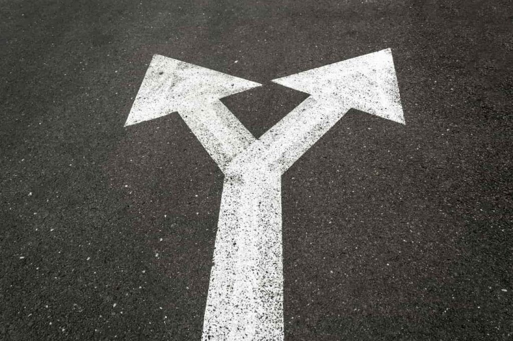 two arrows on blacktop signifying the choice between self managing a rental property or hiring a property manager