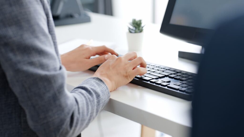 A person sitting in front of a computer using property management software