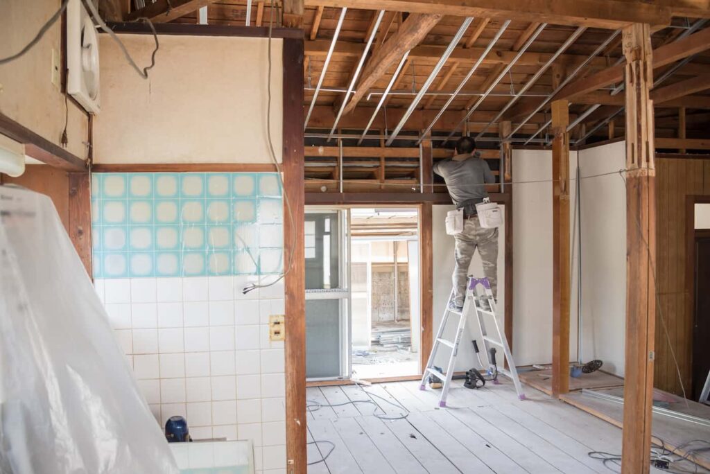 a construction worker standing on a ladder making working on a home renovation project.