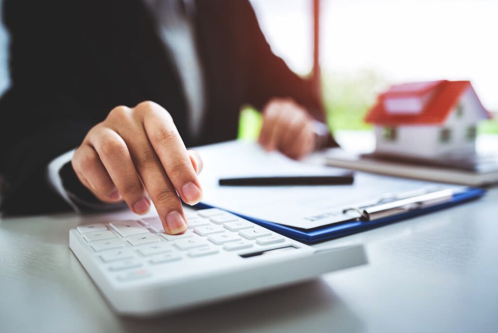 a person in a suit sitting at a desk using a calculator to calculate a rental increase.