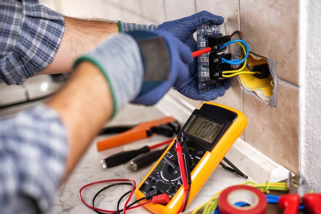 a person wearing gloves replacing an electrical outlet in a kitchen