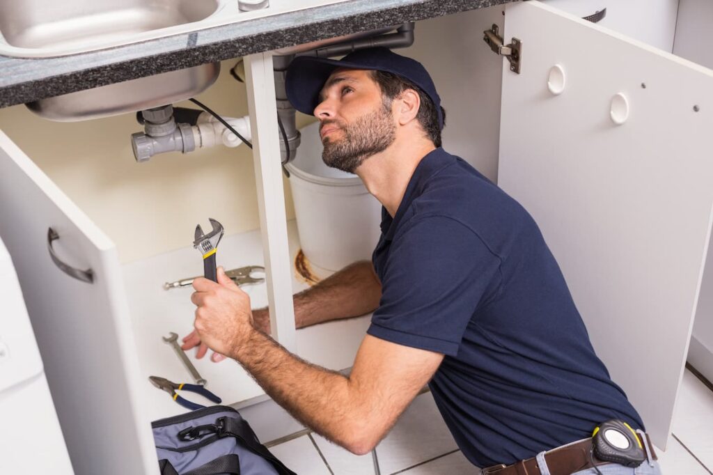 a man working on the plumbing underneath a kitchen sink